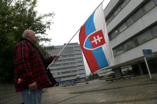 Un partidario del gobierno con una bandera eslovaca, el 17 de mayo de 2024, delante del hospital donde se encuentra ingresado en estado grave el primer ministro, Robert Fico, tras haber sufrido un intento de asesinato cuatro días antes