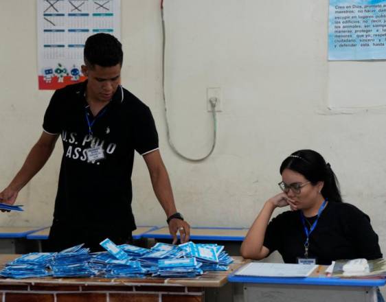 AFP | Un trabajador electoral sostiene boletas durante un conteo manual después del cierre de votaciones.