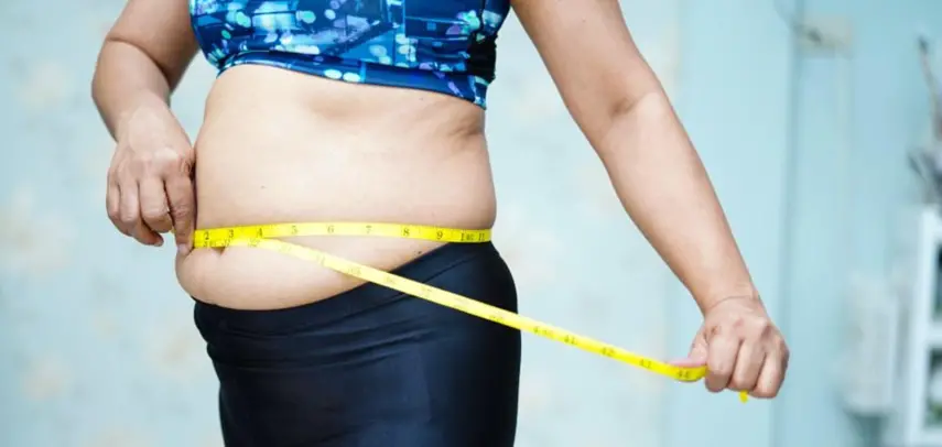 Cortesía | Una mujer se toma medidas de su cintura, que está algo abultada por el sobrepeso.