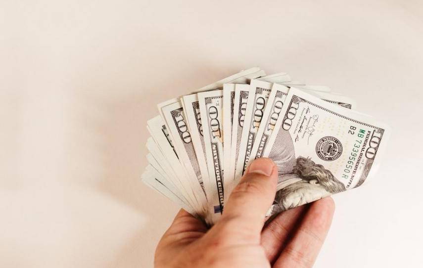 PEXELS | Una persona sostiene varios billetes de 100 dólares.