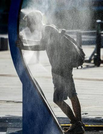 Un hombre se refresca mientras pasa por un rociador de agua instalado en el centro de Bucarest, el 28 de junio de 2026.