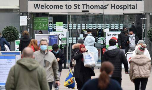 Personas, algunas con cubiertas faciales para combatir la propagación de Covid-19, llegan y salen del hospital St Thomas en el centro de Londres el 23 de diciembre de 2021