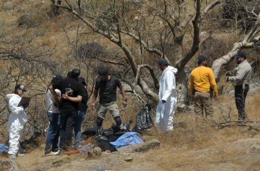 Expertos forenses trabajan con varias bolsas de restos humanos extraídos del fondo de un barranco por un helicóptero, que fueron abandonados en Zapopan, estado de Jalisco, México, el 31 de mayo de 2023.