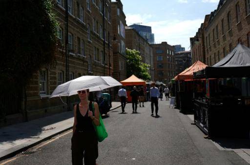 Una mujer se protege del sol bajo un paraguas el 26 de junio de 2026 en el mercadillo de Whitecross, en el este de Londres