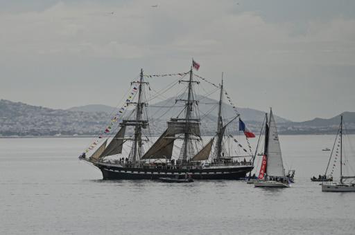 El velero francés Belem, escoltado por pequeñas embarcaciones, sale del puerto de El Pireo rumbo a Francia, con la llama olímpica a bordo, el 27 de abril de 2024 cerca de Atenas