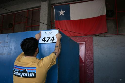 Un empleado municipal pone el cartel indicativo de una mesa electoral en el Estadio Nacional de Santiago el 13 de diciembre de 2025, víspera de la segunda vuelta de las elecciones presidenciales de Chile