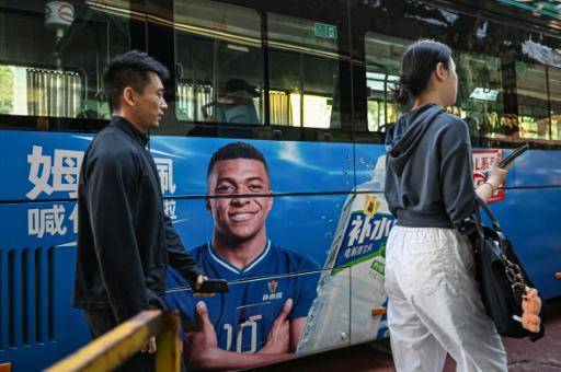 La gente pasa junto a un autobús en el que aparece la estrella del fútbol francés Kylian Mbappé