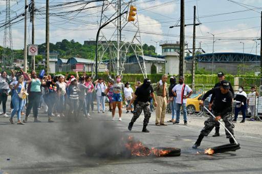 Policías ecuatorianos retiran neumáticos ardiendo de la entrada de una prisión de Guayaquil el 28 de marzo de 2024