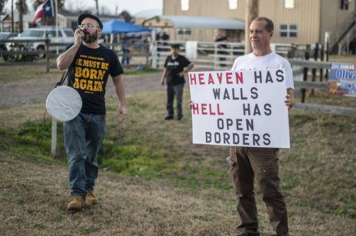 Manifestantes sostienen carteles y hablan a través de un megáfono apoyando al convoy Take our border back que reclama contra la migración irregular, cerca de Cornerstone Childrens Ranch en Quemado, Texas, el 2 de febrero de 2024