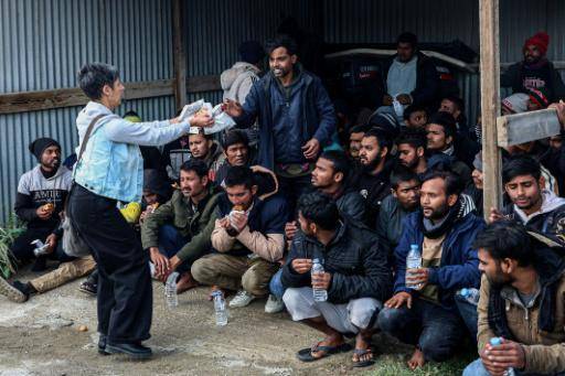 Una mujer ofrece comida y agua a migrantes rescatados por la Guardia Costera Helénica, en la región de Kaloi Limenes, cerca de Heraclión, en la costa sur de Creta, el 21 de febrero de 2026.