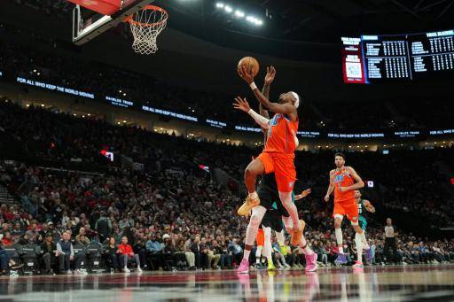 Shai Gilgeous-Alexander, de los Oklahoma City Thunder, se dirige a la canasta bajo la presión de Robert Williams III, de los Portland Trail Blazers, durante la segunda mitad del partido disputado en el Moda Center el 30 de noviembre de 2025 en Portland, Oregón.