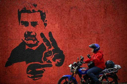(ARCHIVO) Un motociclista pasa frente a un mural del depuesto presidente Nicolás Maduro el 14 de mayo de 2026 en Caracas.