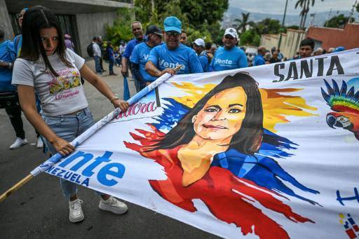 Una partidaria de la líder opositora venezolana y premio Nobel de la Paz María Corina Machado sostiene una pancarta con su retrato frente a la sede del partido VENTE Venezuela en Caracas el 28 de marzo de 2026