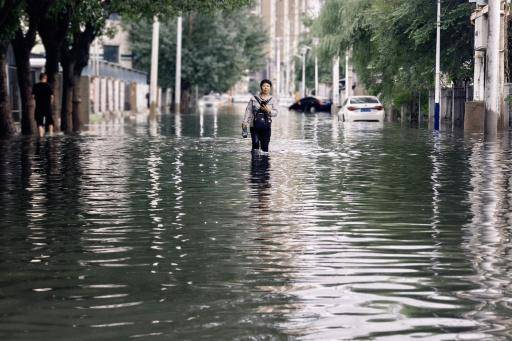 Una mujer camina por una calle inundada a causa de las lluvias torrenciales provocadas por el tifón Bavi, el 14 de julio de 2026 en Shenyang, al noreste de China