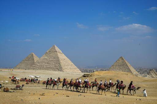 Un grupo de turistas monta en camellos frente a la necrópolis egipcia de las célebres pirámides de Giza, el 7 de noviembre de 2025 cerca de El Cairo