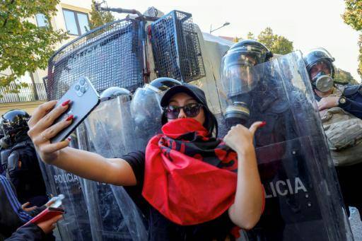 Una manifestante se toma una fotografía delante de la policía antidisturbios el 20 de octubre de 2026 en Tirana