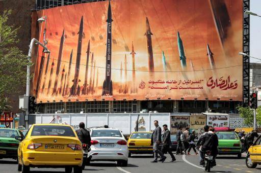 Esta foto del 15 de abril de 2024 muestra el tráfico en Teherán delante de un afiche que exhibe misiles balísticos iraníes