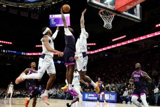 Naz Reid (C), de Minnesota Timberwolves, hunde la pelota ante la marca de Daniel Gafford (D) de Dallas Mavericks, en partido de la NBA jugado en Mineápolis el 20 de febrero de 2026