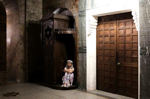 Una mujer, sentada en un confesionario, escucha un concierto de órgano en la Basílica de Nuestra Señora del Rosario del Santuario de Lourdes, en Francia, el 14 de agosto de 2023, durante la celebración de la Asunción