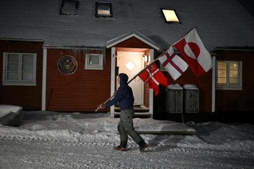 Jens Kjeldsen, exjuez de 70 años ahora dedicado a la carpintería, sostiene una vara con las banderas de Dinamarca, la islas Feroe y Groendandia durante su protesta diaria frente a la sede del Consulado de EEUU, el 20 de enero de 2026 en Nuuk, la capital groenlandesa