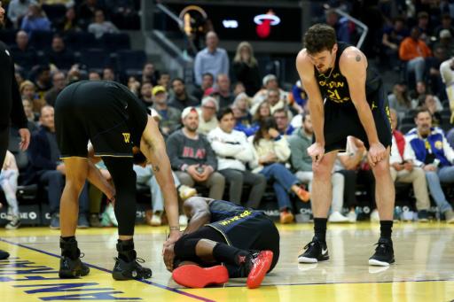 Jimmy Butler se echa la mano a la rodilla tras la acción en que se lesionó, ante la mirada de sus compañeros Stephen Curry (izq) y Quinten Post, durante el partido de la NBA entre los Golden State Warriors y los Miami Heat disputado el 19 de enero de 2026 en San Francisco, al oeste de EEUU