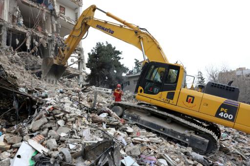 Un bombero iraní dirige una excavadora entre los escombros de un edificio del norte de Teherán destruido el 23 de marzo de 2026