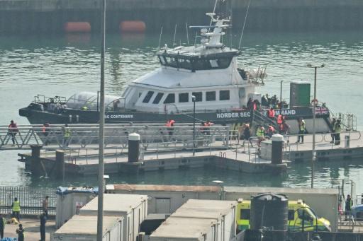 Unos migrantes (con chalecos naranjas) rescatados en el mar mientras intentaban cruzar el canal de la Mancha desde Francia bajan de un barco de la fuerza fronteriza británica en el puerto deportivo de Dover, el 27 de septiembre de 2026 en el sureste de Inglaterra