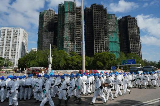 Agentes de policía vestidos con trajes protectores blancos frente a los bloques de viviendas de Wang Fuk Court tras el incendio, el 29 de noviembre de 2025 en Hong Kong