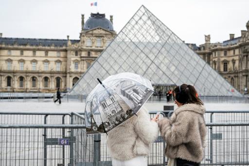 Dos turistas permanecen el 12 de enero de 2026 delante de la Pirámide del museo del Louvre, en París