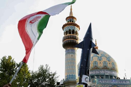 Iraníes enarbolan una bandera y una maqueta de misil tras el ataque con misiles y drones iraníes contra Israel, el 15 de abril de 2024, en el centro de Teherán
