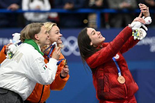 De izquierda a derecha, Arianna Fontana (plata), Xandra Velzeboer (oro) y Courtney Sarault (bronce) haciéndose un selfi en el podio olímpico de 500 m de patinaje short-track de los Juegos de Invierno de Milán-Cortina. En Milán (norte de Italia), el 12 de febrero de 2026