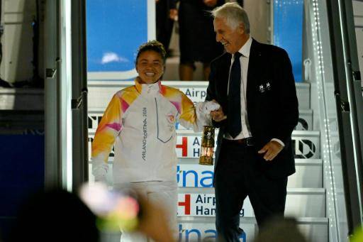 La tenista italiana Jasmine Paolini (izquierda) y Giovanni Malago, presidente del comité de organización de los Juegos Olímpicos de Invierno de Milán-Cortina 2026, sostienen la linterna con la llama olímpica tras aterrizar en el aeropuerto Fiumicino de Roma, el 4 de diciembre de 2025