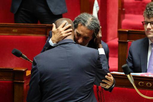 El diputado ecologista Steevy Gustave abraza al centrista Max Mathiasin (de espaldas) tras aprobarse por unanimidad la derogación de las leyes que definían a los esclavos como bienes muebles, el 28 de mayo de 2026 en la Asamblea Nacional francesa, en París