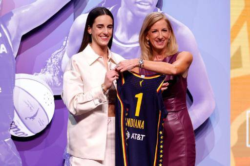 Caitlin Clark (izquierda) posa con su nuevo uniforme al lado de la comisionada de la WNBA, Cathy Engelbert.