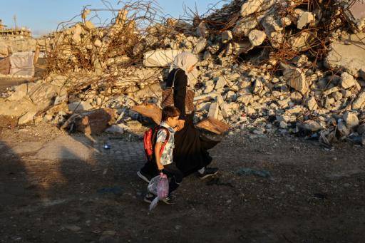 Una mujer palestina y un niño pasan delante de unos edificios destruidos de camino al colegio en Ciudad de Gaza el 19 de septiembre de 2026