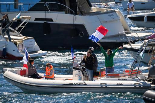 Unos espectadores navegan para recibir al velero Belem, que transporta la llama olímpica, cerca de Marsella, en el sur de Francia, el 8 de mayo de 2024