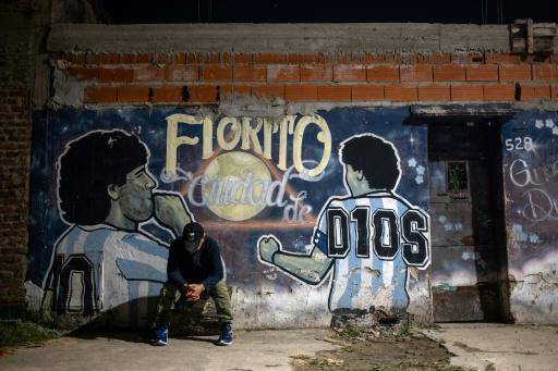 Un hombre se sienta frente a un mural que representa a Diego Maradona en el patio de la casa de la infancia del difunto futbolista, ahora transformada en un comedor benéfico comunitario, en Villa Fiorito, Argentina, el 9 de abril de 2026