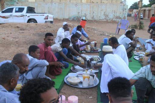 Unos sudaneses comparten rompen el ayuno del ramadán el 18 de febrero de 2026 en una calle del barrio de Al Hattana, en Omdurman