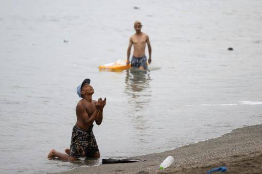 Una persona migrante hace gestos en la playa cerca de la frontera con Marruecos para entrar en el enclave español de Ceuta, en el norte de África, el 31 de julio de 2026