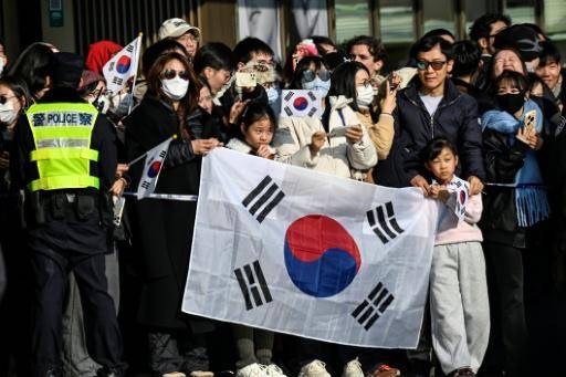 Personas con banderas de Corea del Sur aguardan a ver al presidente Lee Jae Myung durante su visita a Shanghái, el 7 de enero de 2026 en la ciudad china