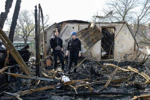 Dos jóvenes pasan sobre los escombros de su vivienda, en un edificio residencial de tres plantas, tras un ataque ruso con drones, el 24 de abril de 2026 en Odesa, al sur de Ucrania