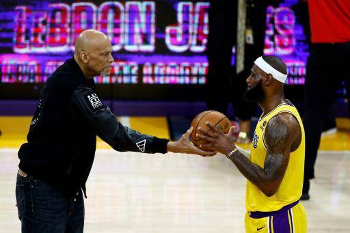 Kareem Abdul-Jabbar (derecha) le entrega la pelota a LeBron James en el homenaje por batir el récord de anotación de la NBA.