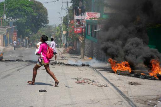 Una mujer corre con un niño en brazos en medio de sonidos de disparos el 20 de marzo de 2024 en Puerto Príncipe