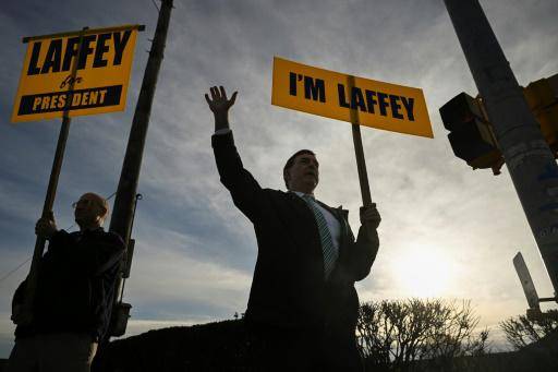 El candidato a las primarias republicanas para las presidenciales de 2024 Steve Laffey (C) saluda a los conductores en una intersección de Cranston, estado de Rhode Island, el 17 de marzo de 2023