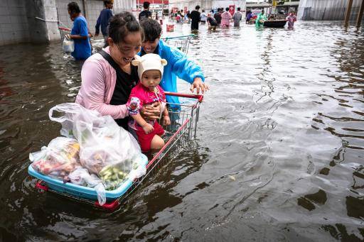 Unas personas avanzan con un carro de supermercado por una calle inundada del distrito de Bang Kapi tras hacer la compra, el 28 de septiembre de 2026 en Bangkok, la capital tailandesa