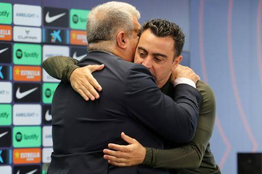 El presidente del FC Barcelona Joan Laporta (izquierda) abraza al técnico Xavi Hernández tras la conferencia de prensa ofrecida ambos para explicar la continuidad del entrenador, en las instalaciones del club en Sant Joan Despí, cerca de Barcelona, el 25 deabril de 2024