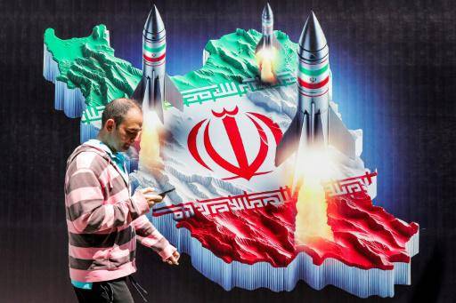 Un hombre pasa frente a un cartel de unos misiles lanzados desde un mapa de Irán con su bandera nacional, el 15 de abril de 2024 en el centro de Teherán