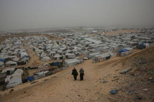 Dos mujeres caminan hacia unas tiendas de desplazados internos en Jan Yunis el 14 de febrero de 2026