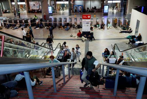 Unos pasajeros se tumban en el suelo para pasar la noche en la estación de trenes de Atocha, en Madrid, tras el apagón masivo del 28 de abril de 2026