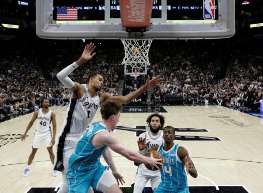 Kon Knuppel le pasa el balón a su compañero de los Charlotte Hornets Moussa Diabate (drcha.) mientras el jugador de los Spurs Victor Wembanyama intenta taponar en su partido de la NBA, en San Antonio (Texas, EEUU), el 14 de marzo de 2026